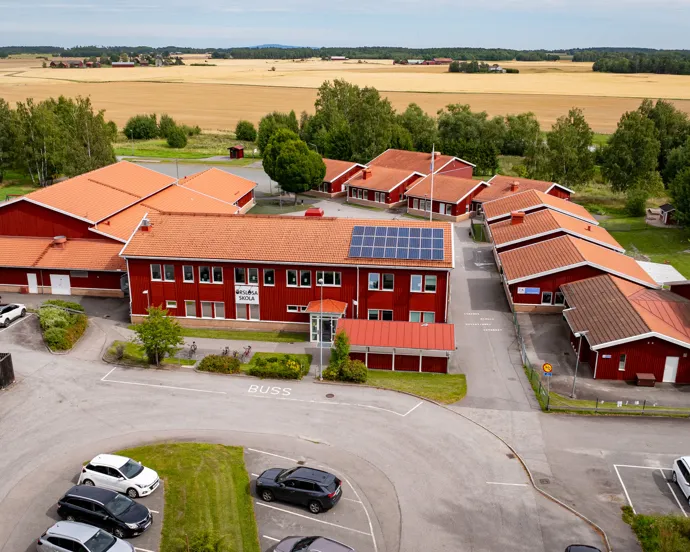 En flygbild av en röd byggnad med bilar parkerade framför den.