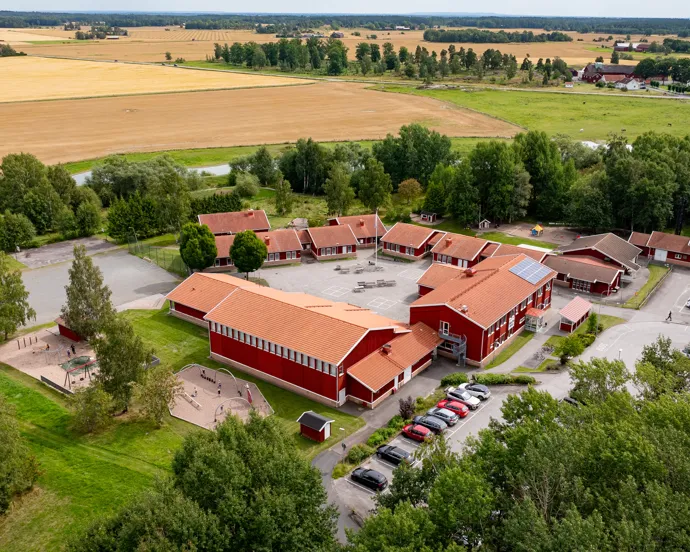 En flygbild av en röd skolbyggnad byggnad omgiven av träd.